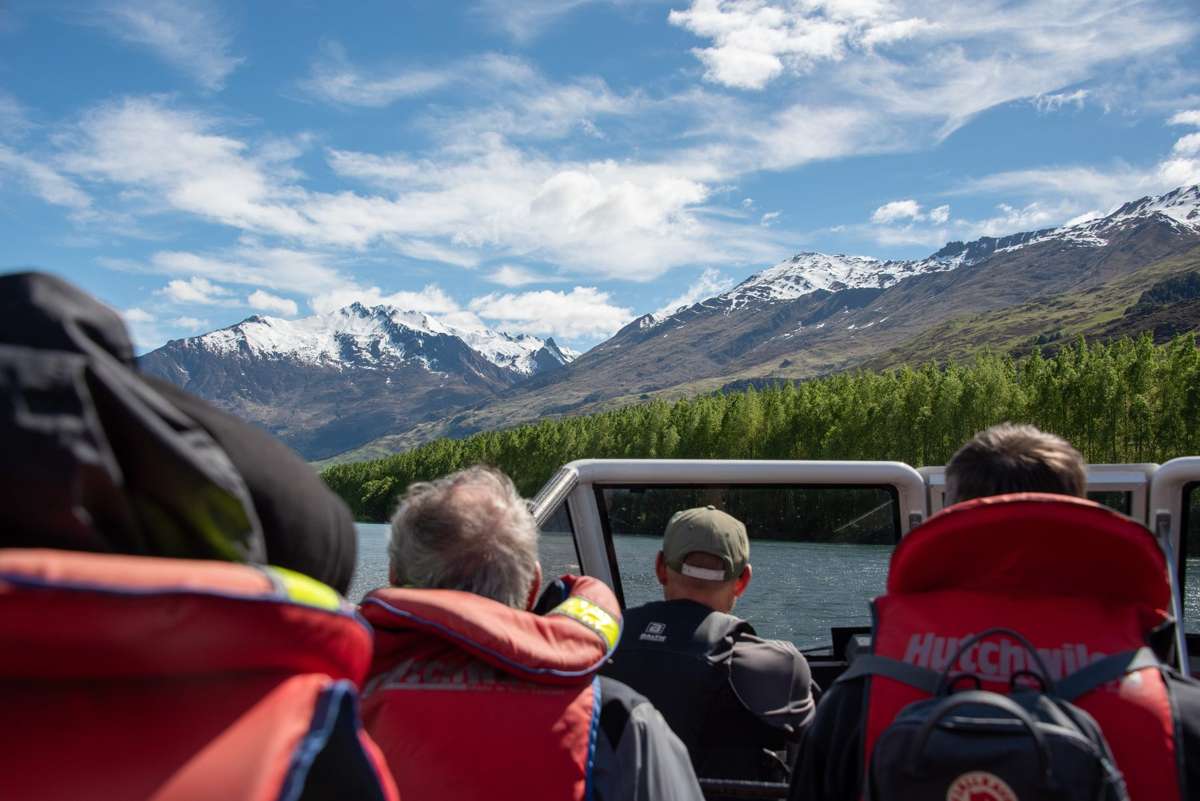 Guests in red life jackets on the jet boat heading up the Matukituki Valley towards the mountains