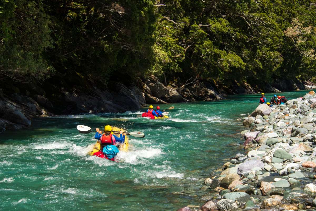 Packrafts on turquoise water between bush-clad banks on the Matukituki River