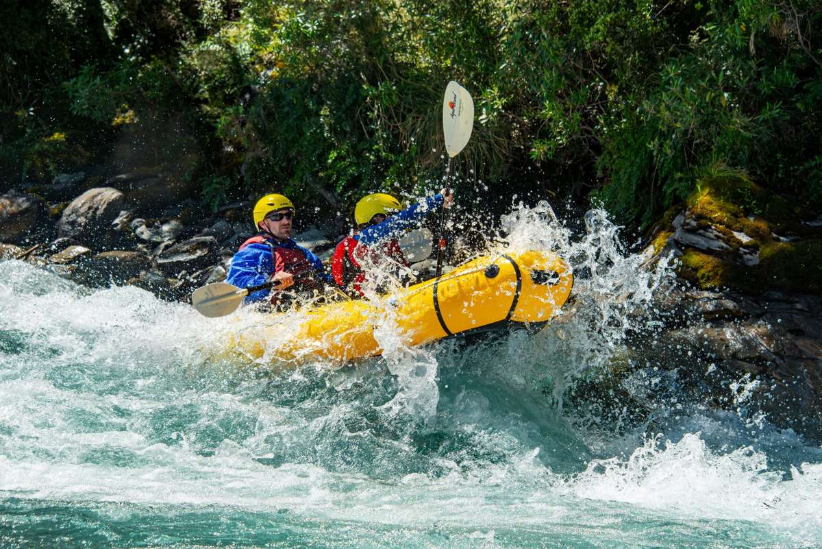 Two paddlers in a packraft hitting whitewater on the Matukituki