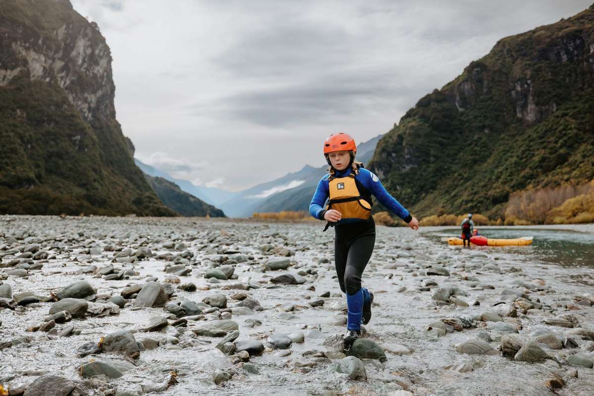 Guide carrying a packraft across the riverbed in the Matukituki Valley